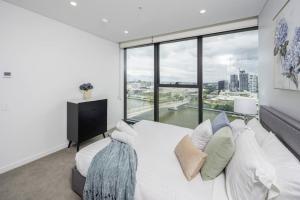 um quarto com uma cama branca e uma grande janela em 1404 Sophistication and Luxury on the Brisbane River by Stylish Stays em Brisbane