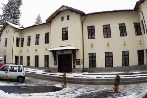 un bâtiment dans la neige avec une voiture garée devant dans l'établissement Regal 1880, à Sinaia