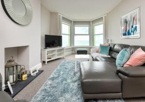 a living room with a leather couch and a television at Sealight in Pwllheli