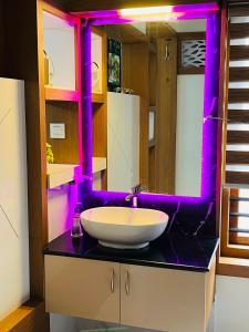 a bathroom with a white sink and purple lighting at Milaano Orchids, Service Villa, Kammana Mananthavady in Wayanad