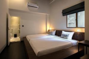 a large white bed in a room with a bathroom at Beanstalk Bangkok in Bangkok