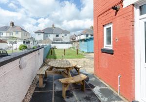 a patio with a table and benches next to a building at Ger y Mor in Porthcawl