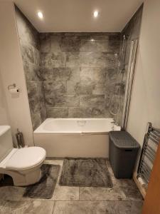 a bathroom with a tub and a toilet and a sink at Beautiful 4 bedroom home with private parking in West Thurrock