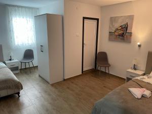 1 Schlafzimmer mit 2 Betten und einer Tür mit 2 Stühlen in der Unterkunft Restaurant - Rooms "Pače 027" Restoran - Prenociste in Kuršumlija