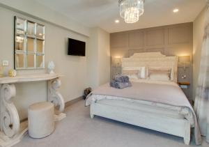 a bedroom with a large white bed and a chandelier at Mulberry Cottage in Conwy