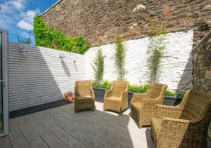 a patio with wicker chairs and a wall at Mulberry Cottage in Conwy