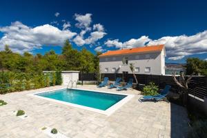 a swimming pool with chairs and a house at Apartment PATRICK with private pool in Čižići