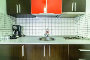 a kitchen counter with a sink and red cabinets at Vila Sia in Bucharest