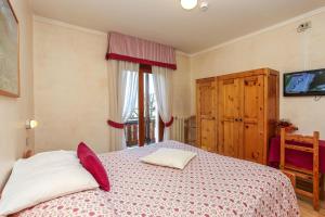 a bedroom with a bed with red pillows and a tv at Albergo Adele in Bormio