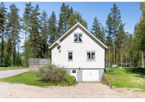 Biały dom z garażem przed drzewami w obiekcie Dream of Dalarna by Tanja w mieście Vansbro