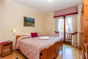 1 dormitorio con 1 cama con colcha roja y blanca en Albergo Adele, en Bormio