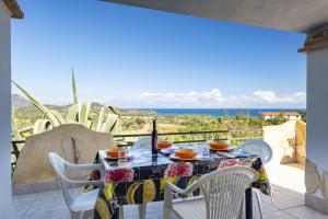 una mesa y sillas en un balcón con vistas al océano en Villa Sole en Tertenìa