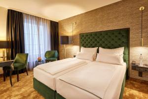 a hotel room with a large bed and a desk at Das Carls Hotel in Düsseldorf +42 photos