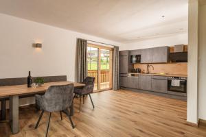 kuchnia i jadalnia z drewnianym stołem i krzesłami w obiekcie Appartements Die Ramsauerin w mieście Ramsau am Dachstein