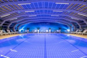 een groot zwembad met stoelen en een plafond bij Hotel Atlantic in Riccione