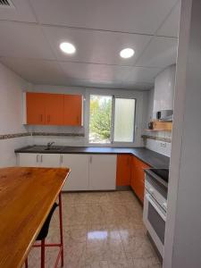 a kitchen with orange and white cabinets and a wooden table at Casa Blanca in Murcia