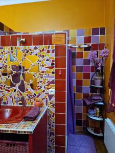 La salle de bains est pourvue d'un lavabo rouge et d'un mur en carrelage coloré. dans l'établissement La Villa des Violettes, à Toulouse