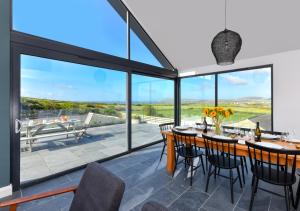 a dining room with large windows and a table with chairs at Geufron House in Aberdaron