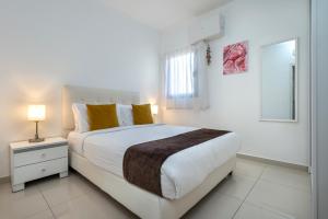 a white bedroom with a large bed and a window at מלוני דירות נופש אילת - Melony Apartments Eilat in Eilat