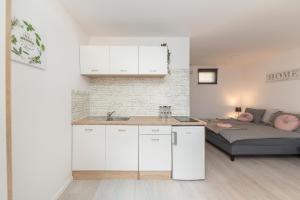 kuchnia z białymi szafkami i łóżko w pokoju w obiekcie Apartments Berni w Lublanie