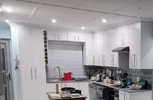una cucina con armadi bianchi e piano cottura di Marina Sands 13A a Jeffreys Bay