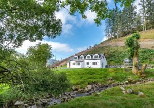 a white house on top of a hill with a river at Esgair Wen in Pentre-briwnant