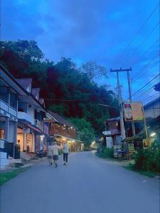 dos personas caminando por una calle en un pueblo en Pakbeng Guesthouse en Pakbeng