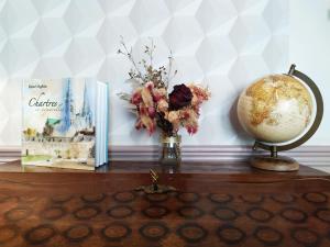 a table with a book and a globe and a vase of flowers at L'Echappée Belle in Chartres