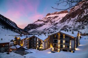 a hotel in the snow with a mountain in the background at Chalets Izia - Village Montana in Val dʼIsère