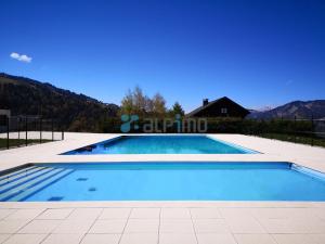 uma grande piscina azul com uma casa ao fundo em Appartement Notre-Dame-de-Bellecombe, 1 pièce, 3 personnes - FR-1-595-18 em Notre-Dame-de-Bellecombe