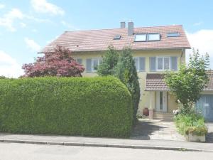 ein gelbes Haus mit einer Hecke davor in der Unterkunft Gästezimmer Gross in Tübingen