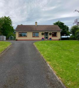 a house with a driveway in front of a yard at Lily's - 3 Bedroom Country Cottage with Large Garden in Sligo