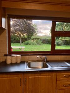 a kitchen sink and a window with a view of a park at Lily's - 3 Bedroom Country Cottage with Large Garden in Sligo