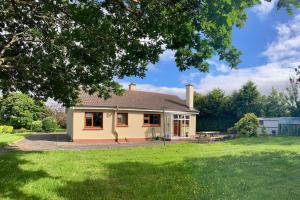 una pequeña casa amarilla con un patio verde en Lily's - 3 Bedroom Country Cottage with Large Garden en Sligo