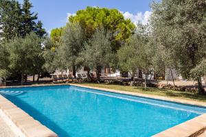 una piscina azul con árboles en el fondo en Finca Can Lluc en Alaró