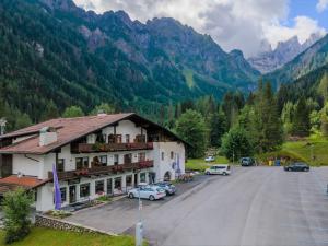 a building with cars parked in a parking lot with mountains at Ciasa Molino 306 in Falcade +8 photos
