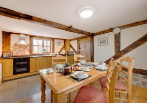 uma cozinha com uma mesa de madeira e cadeiras num quarto em Stabal y Copa em Llanllugan
