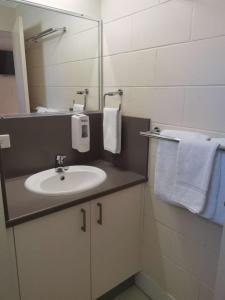 a bathroom with a sink and a mirror and towels at Nambour Lodge Motel in Nambour