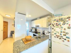 a kitchen with a white refrigerator and a sink at Bahia Blanca Arenales del Sol by Villas&You in Arenales del Sol