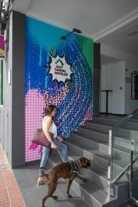 a woman walking a dog in front of a mural at Casual Pop Art Benidorm in Benidorm