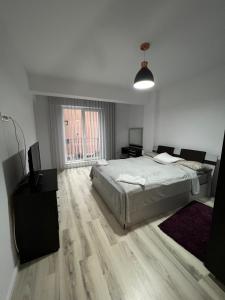 ein weißes Schlafzimmer mit einem Bett und einem TV in der Unterkunft Apartament de lux intr-o zona rezidentiala linistita in Iaşi