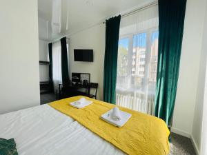 a bedroom with a bed with a yellow blanket and a window at Green apartments Easy Kaunas in Kaunas