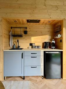 a kitchen with white cabinets and a black dishwasher at beGLAMP - Glamping nad Zalewem Próba in Brzeźnio