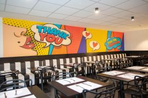 a dining room with tables and chairs with thank you mural at Casual Pop Art Benidorm in Benidorm
