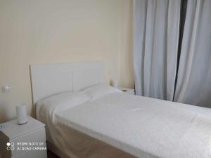 1 dormitorio con cama blanca y ventana en Precioso apartamento Campo Golf, en Huesca