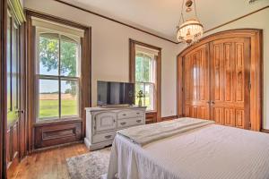 a bedroom with a bed and a tv and windows at Spacious Farmhouse on 200 Acres Along the River in Edgerton