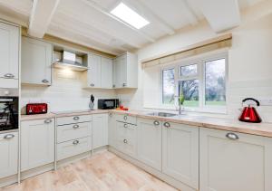 a kitchen with white cabinets and a red appliance at Pwllglas in Darowen