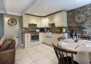 a kitchen with a table and a couch and a table and chairs at Marina Beach Cottage in Pwllheli