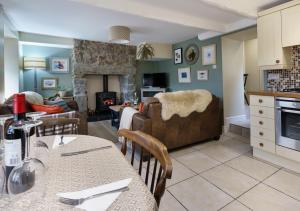 a kitchen and living room with a table and a couch at Marina Beach Cottage in Pwllheli