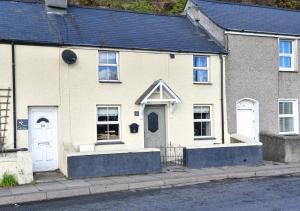 a white house with white doors on a street at Marina Beach Cottage in Pwllheli